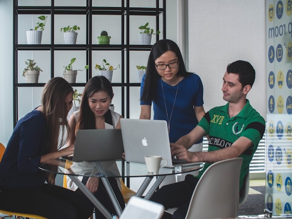 A team of professionals collaborating around a laptop in a modern office setting.