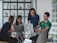 A diverse group of professionals collaborating around laptops in a modern workspace.