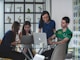 A professional meeting between web developers discussing project plans around a laptop.