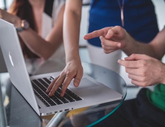 person touching and pointing MacBook Pro