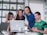 A group of diverse college students collaborating enthusiastically around a laptop.