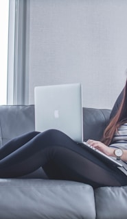 woman sitting on sofa while using MacBook Pro