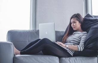 woman sitting on sofa while using MacBook Pro