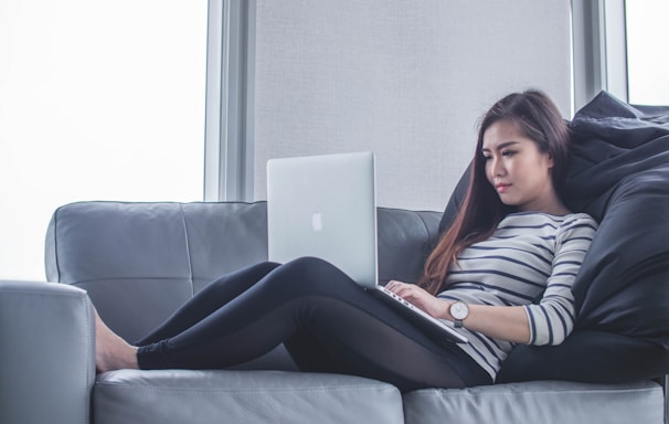 woman sitting on sofa while using MacBook Pro