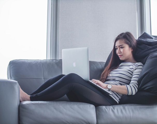 woman sitting on sofa while using MacBook Pro