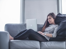 woman sitting on sofa while using MacBook Pro