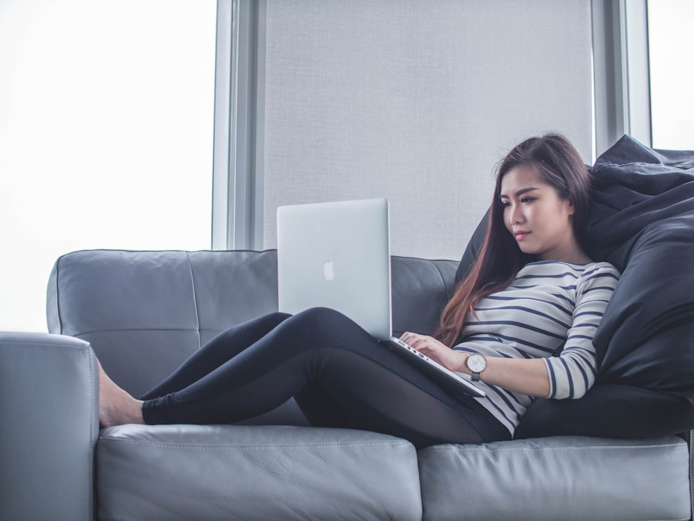 MacBook Pro를 사용하는 동안 소파에 앉아있는 여자