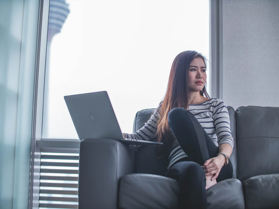 A woman sitting on a sofa using a laptop