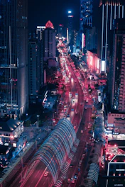 A nighttime cityscape of Tunisian streets glowing under red and black neon lights.