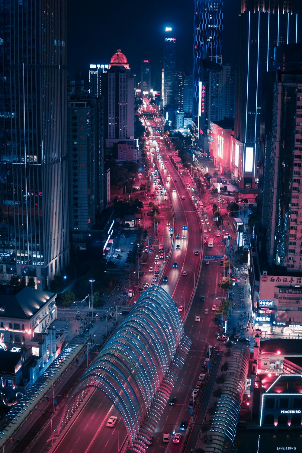 야간에 고층 건물 사이의 도로 근처를 주행하는 차량의 타임랩스 사진