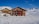 Photo of a smiling cleaning team working on mountain chalet windows with snowy alpine background.