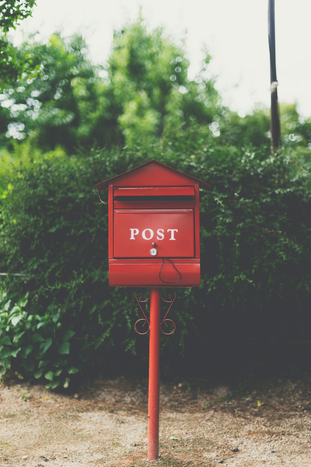 Boîte aux lettres en bois rouge près de la plante à feuilles vertes