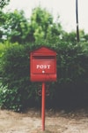 red wooden mailbox near green leaf plant