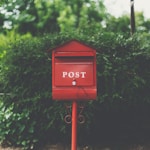 red wooden mailbox near green leaf plant
