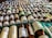 Rows of small bottles with white caps and labels, possibly containing homeopathic remedies, are arranged in a neatly organized manner on a green surface.