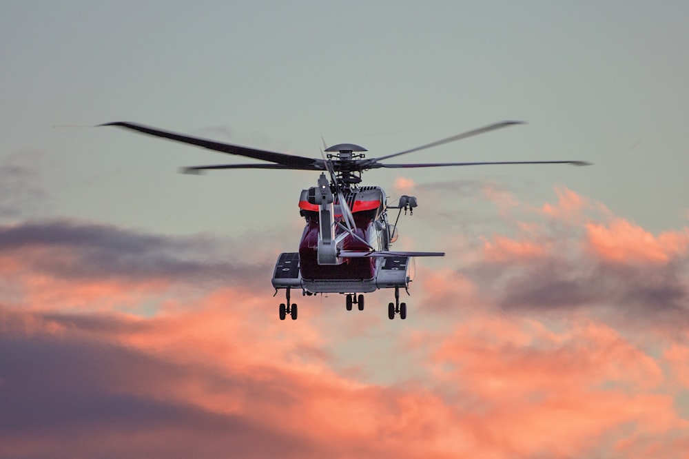 Hélicoptère en vol stationnaire rouge et blanc en plein vol