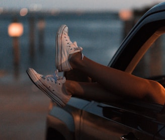 selective focus photography of person wearing white low-top sneakers inside vehicle