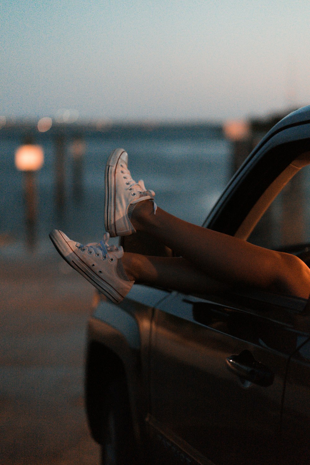 Fotografía de enfoque selectivo de una persona que lleva zapatillas blancas de caña baja dentro del vehículo