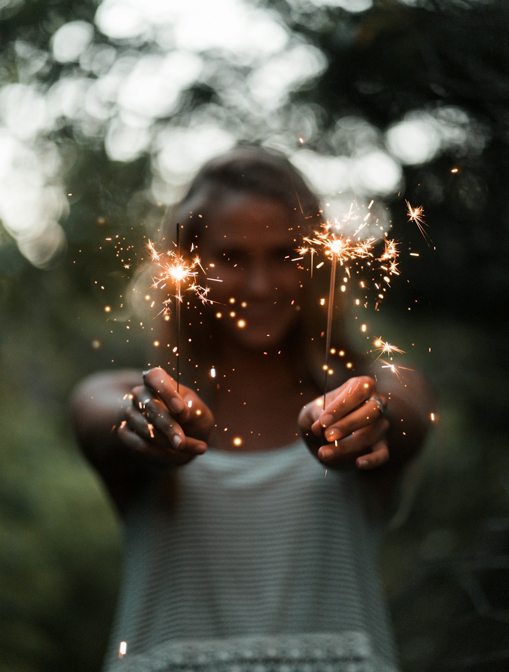 selective focus photography of woman holding two sparklers