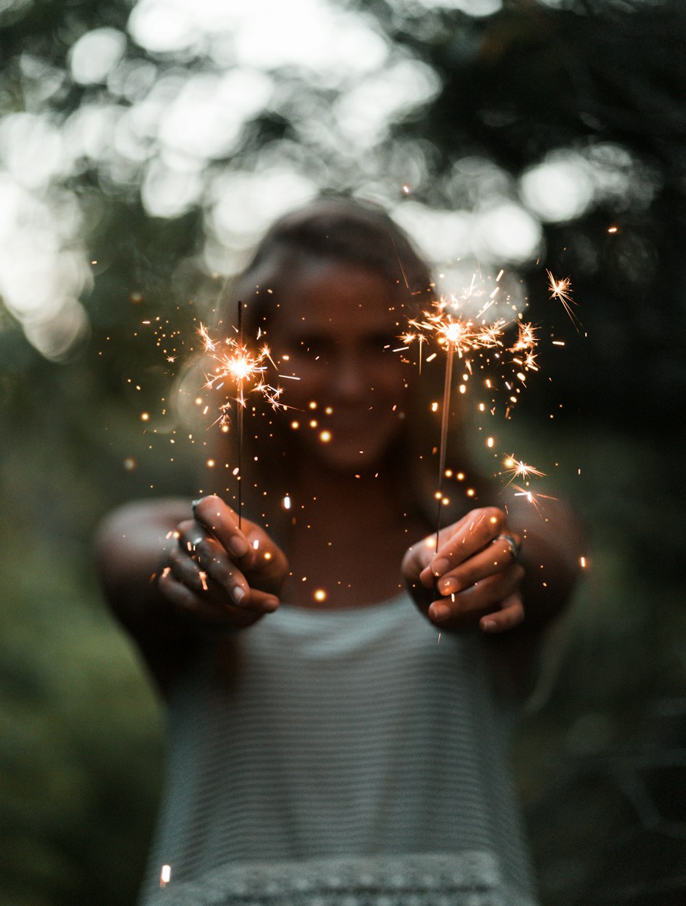 Selektive Fokusfotografie einer Frau, die zwei Wunderkerzen in der Hand hält