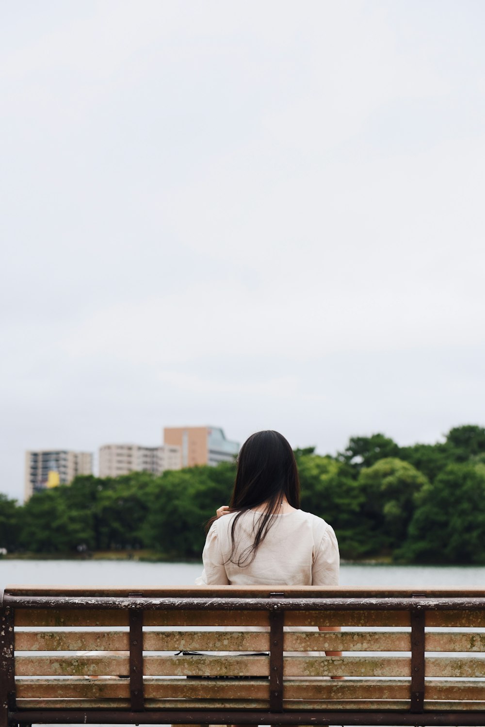 一人でベンチに座っている白いトップスの女性