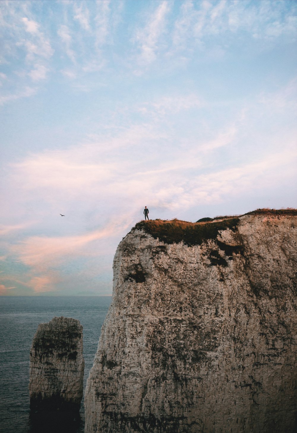 silhouette of standing man on top of rock formation near body of water