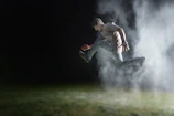 A powerful shot of a male athlete doing a dynamic jump squat under dramatic lighting with red neon glow effects.
