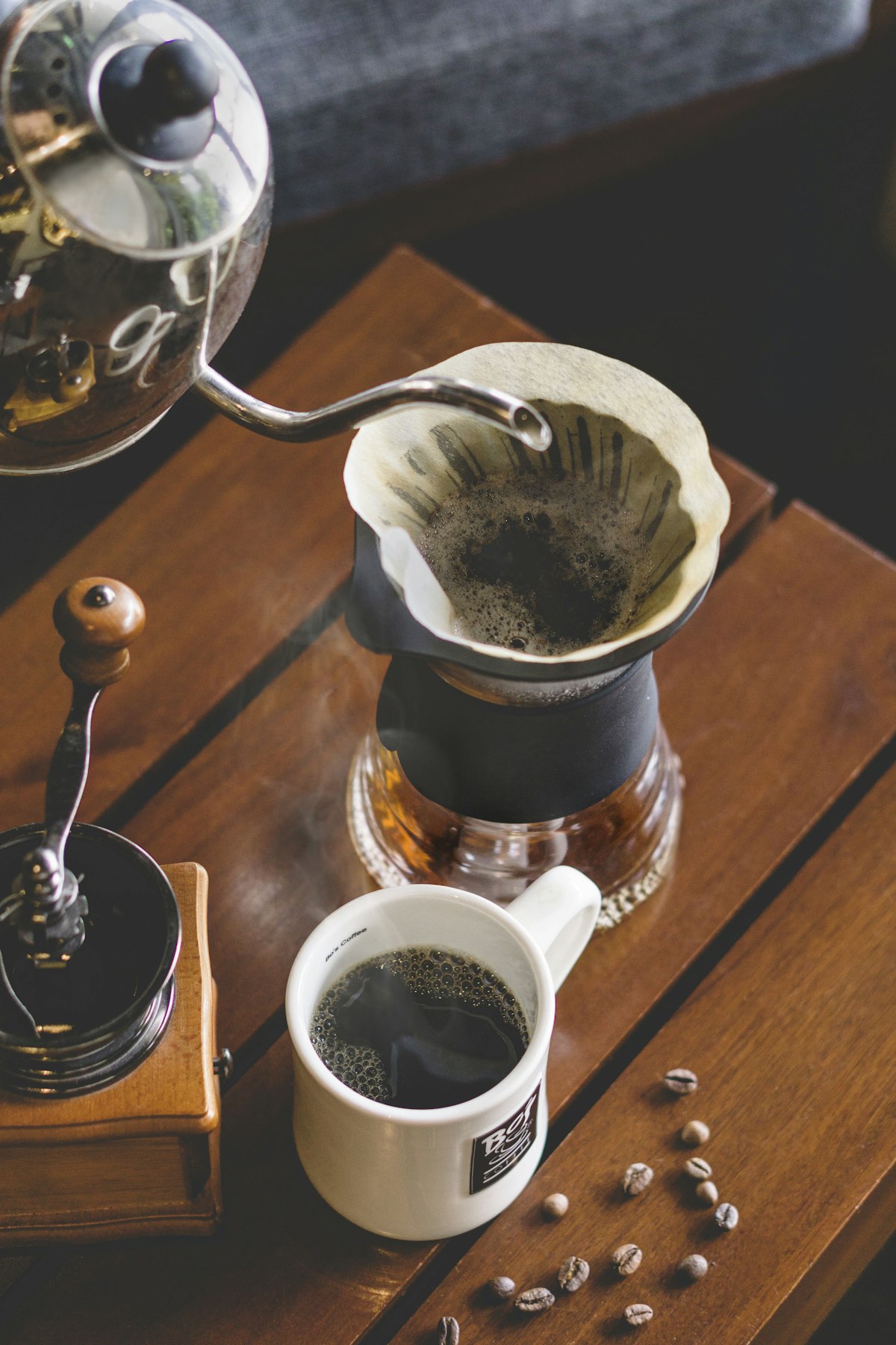 A dark moody scene of a coffee grinder beside freshly brewed coffee on a counter
