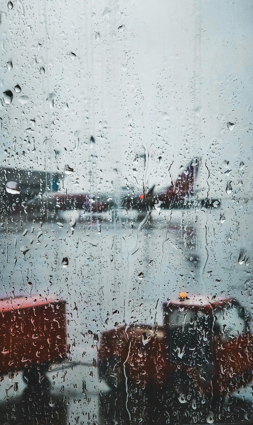 Fotografía de enfoque selectivo de panel de vidrio con gotas de lluvia con vista de avión de cercanías