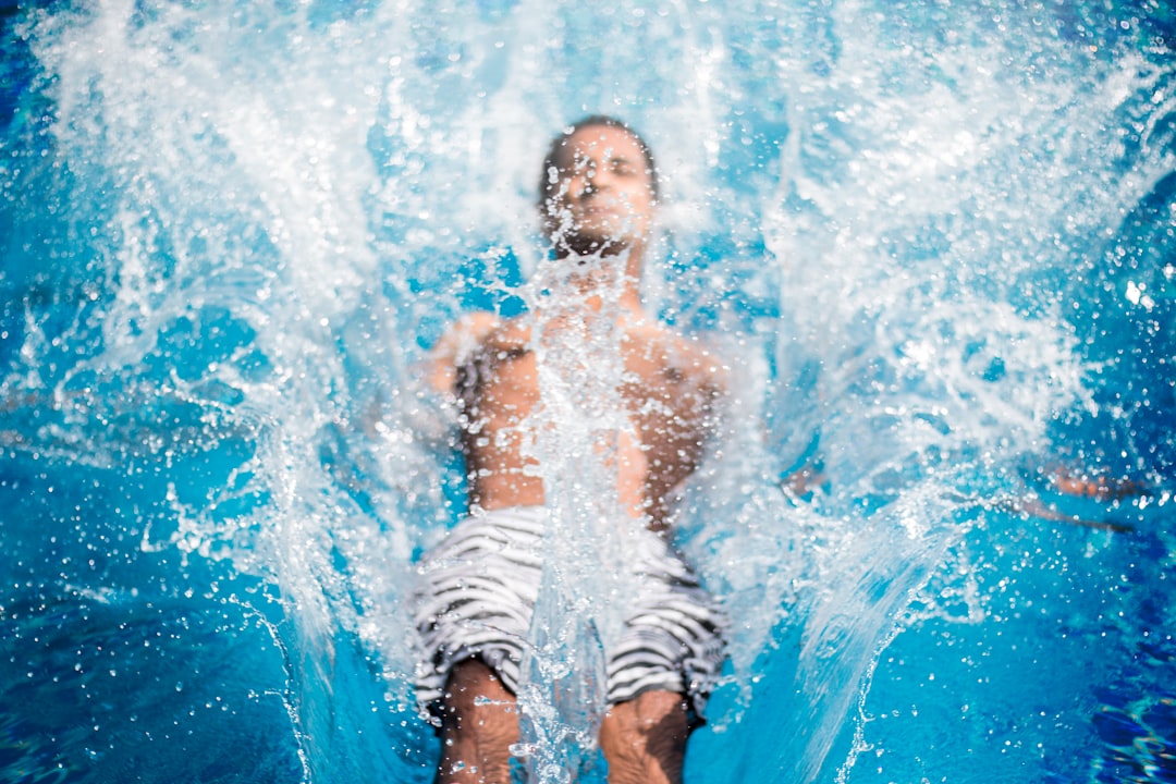 man falling on blue body of water