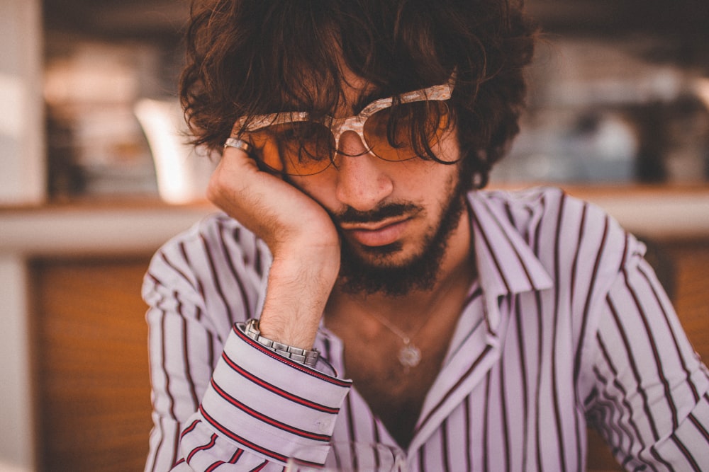 person wearing a white and brown dress shirt holding his face