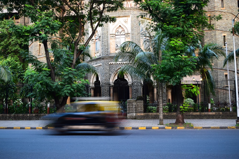 black and yellow vehicle passing by near beige concrete building