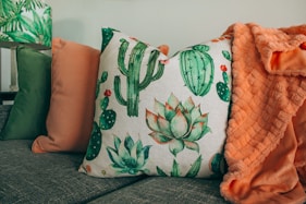 three green, orange, and white throw pillows on sofa