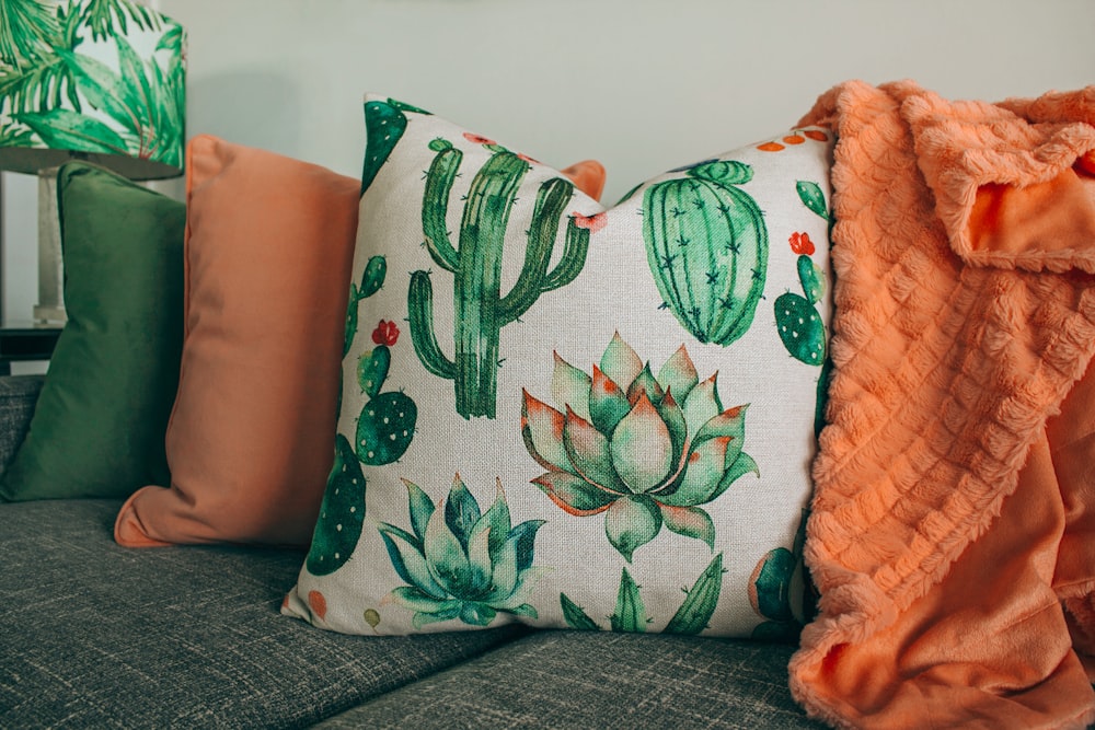 ソファに緑、オレンジ、白のひざ掛け枕を3つ