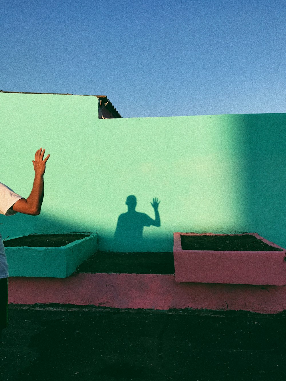 Persona agitando la sombra reflejando en la pintura de la pared verde azulado