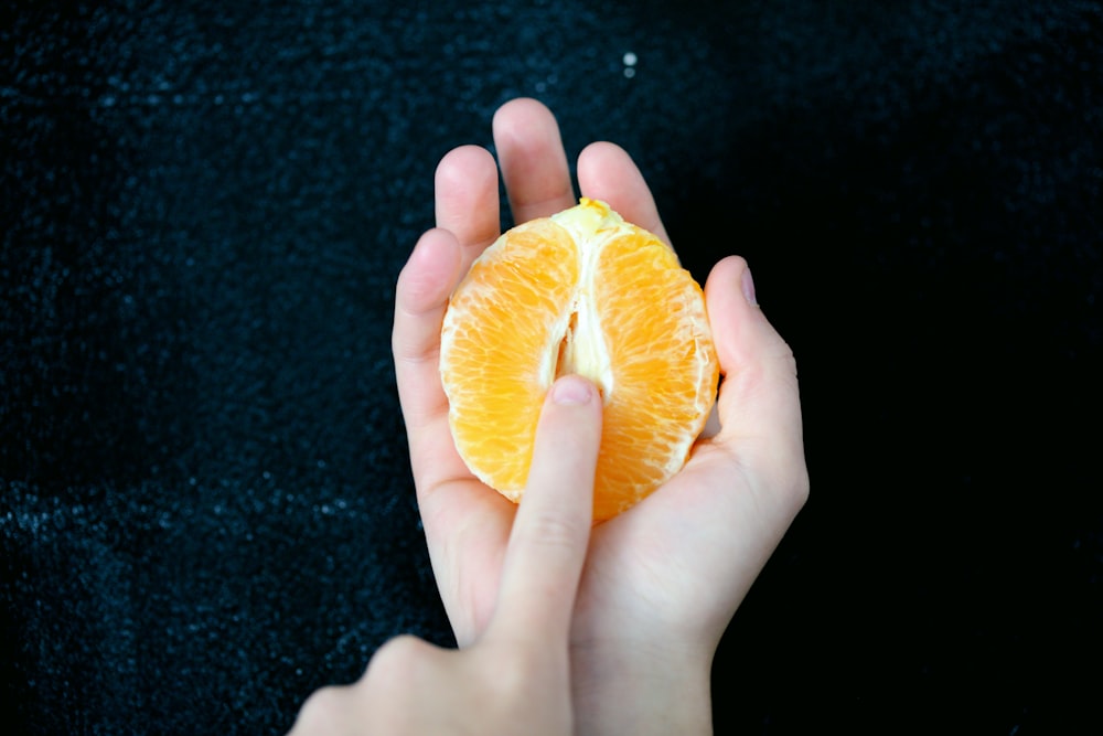 Person, die in Scheiben geschnittene Orangenfrüchte hält