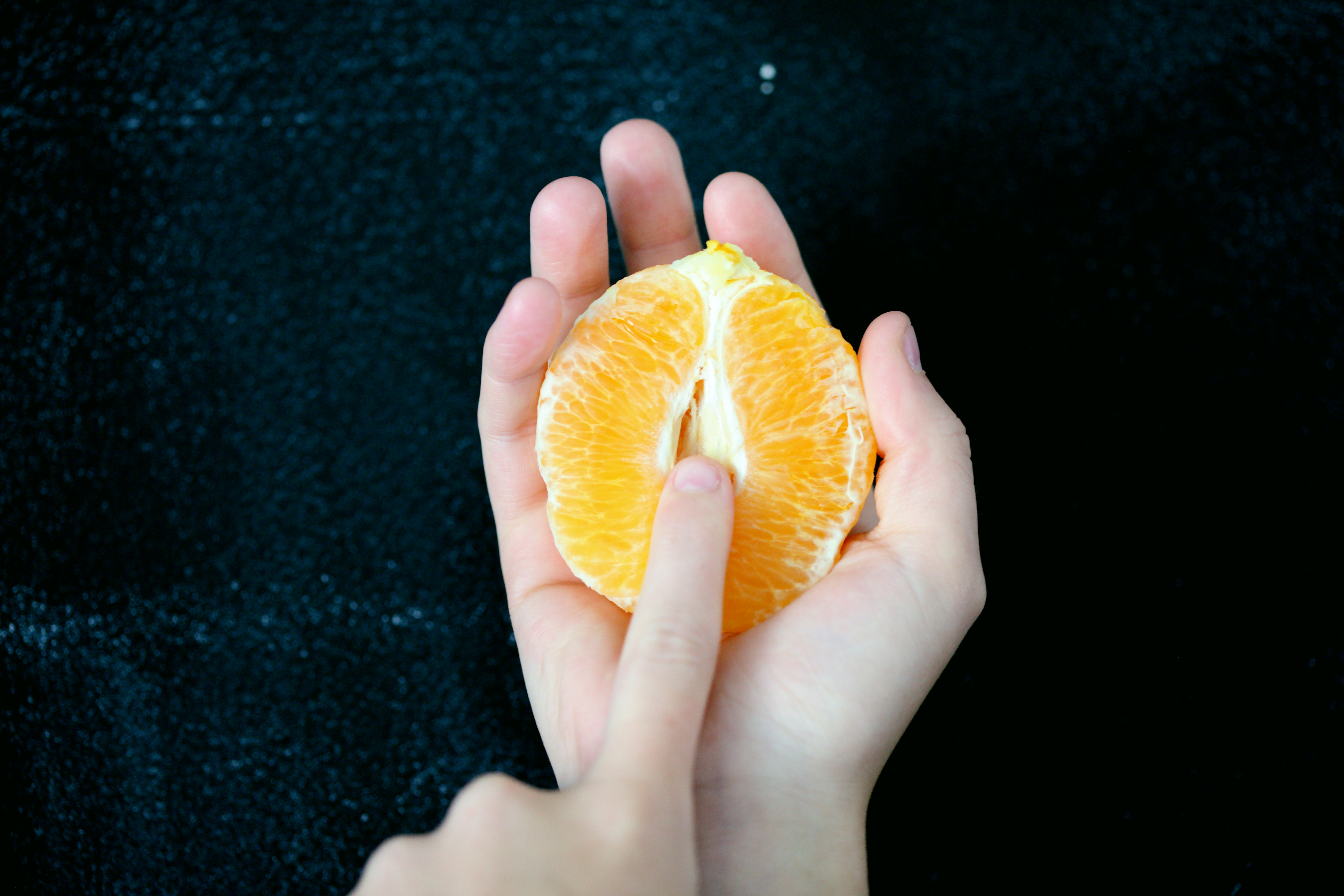 An image of a young person holding a ripe orange to show the similarity of the female genitalia.