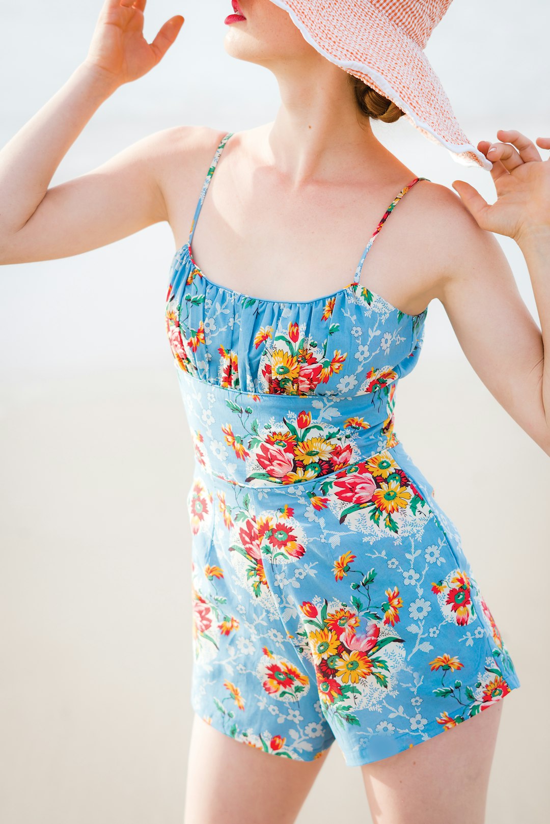 woman wearing blue floral rompers and brown hat