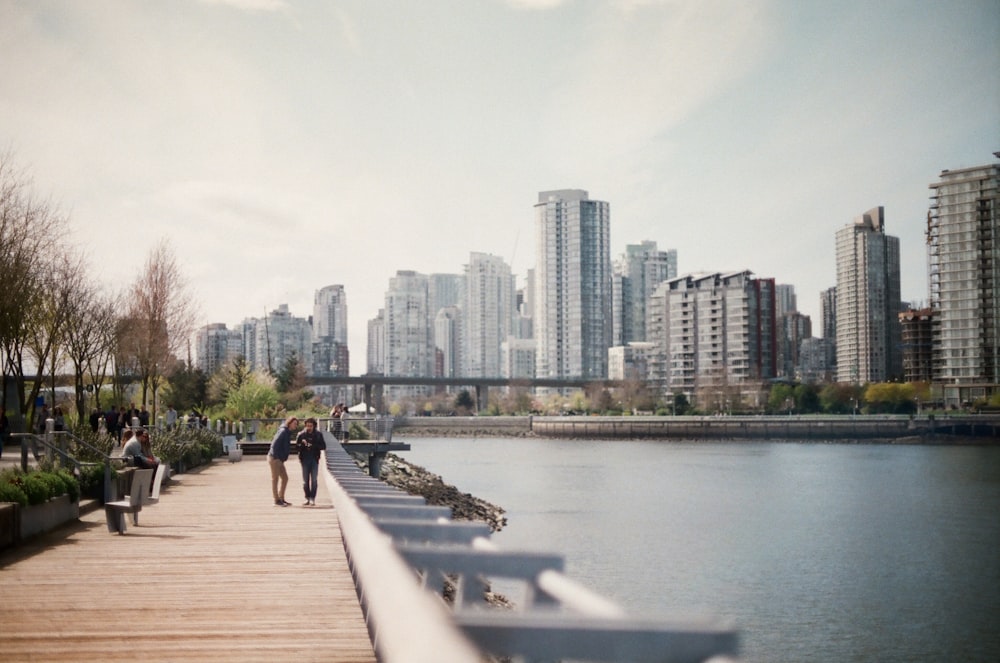 two women walking on brown dock near body of water