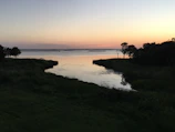 A peaceful lakeside scene at dusk with a lone figure playing a flute, reflecting the harmony of nature and music.