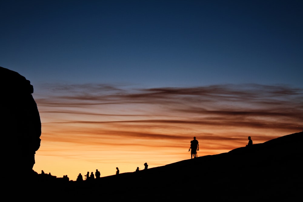 silhouette of people on mountain under blue sky during sunset