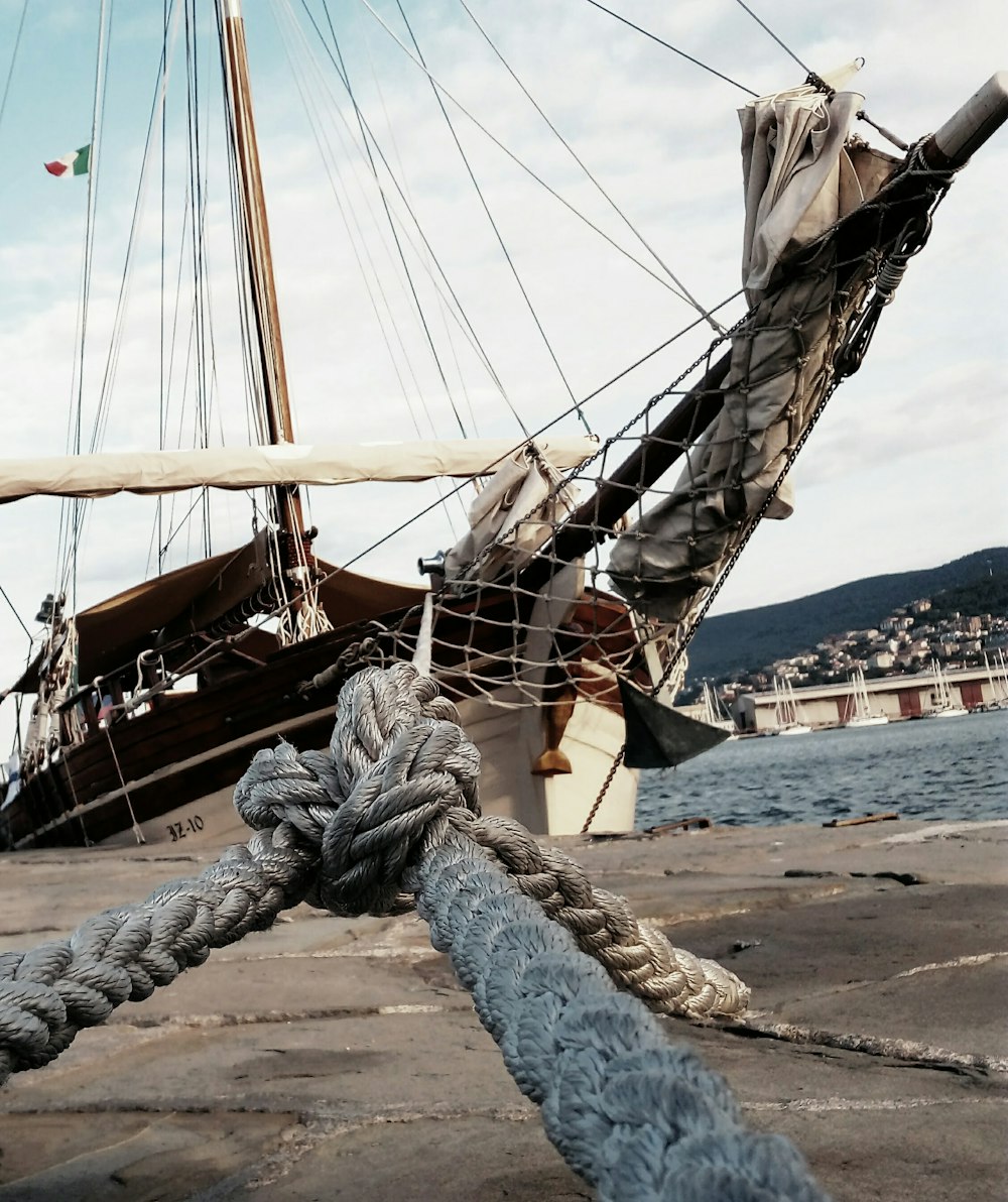 white and brown boat tied on concrete ground