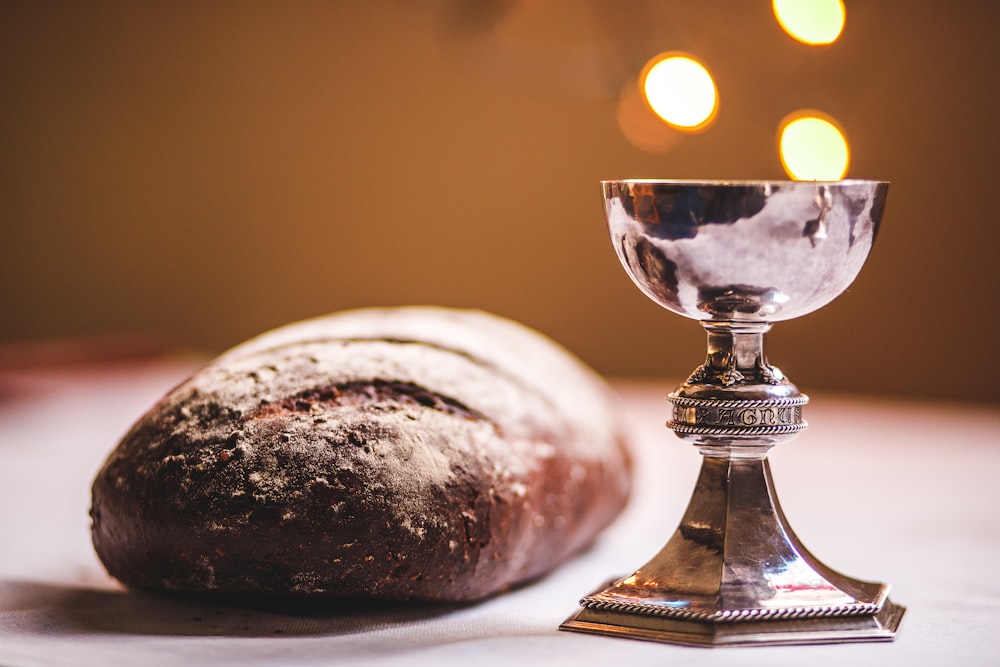 Becher mit grauen Füßen neben Baguettebrot