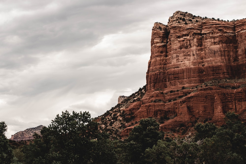 landscape photography of mountain near trees under cloudy sky