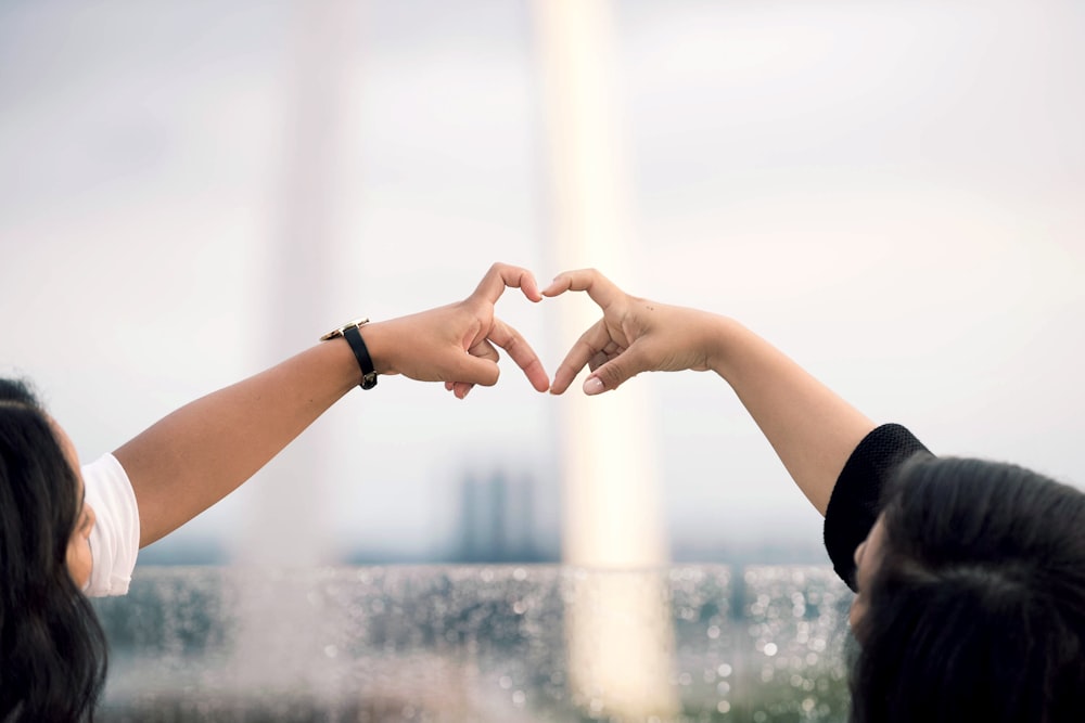 deux personnes faisant le signe de la main de coeur pendant la journée