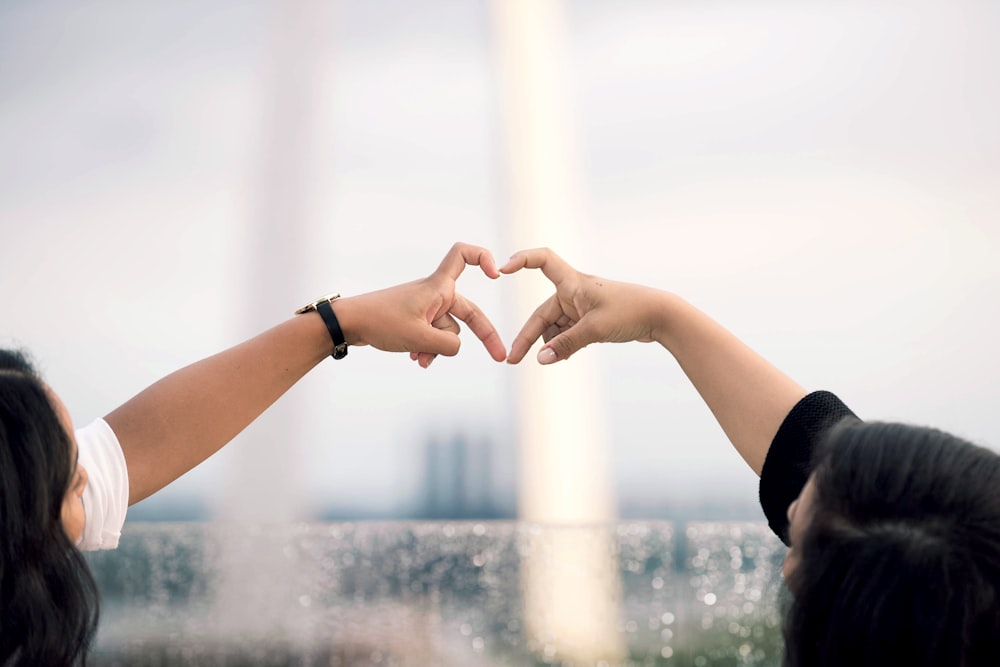 two person doing heart hand sign during daytime
