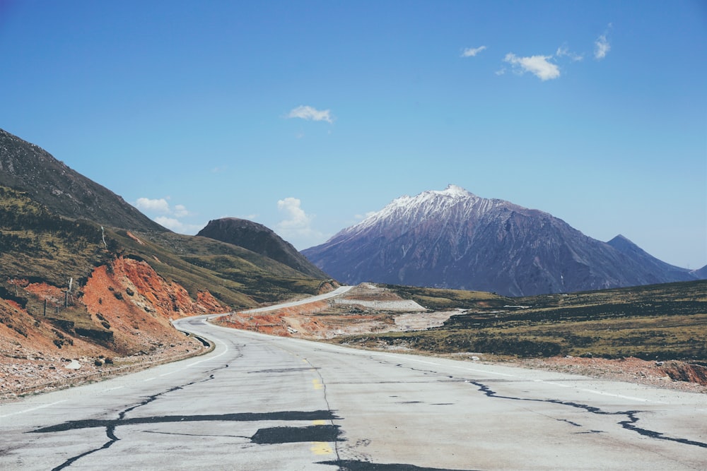 Strada tra la montagna e l'erba verde