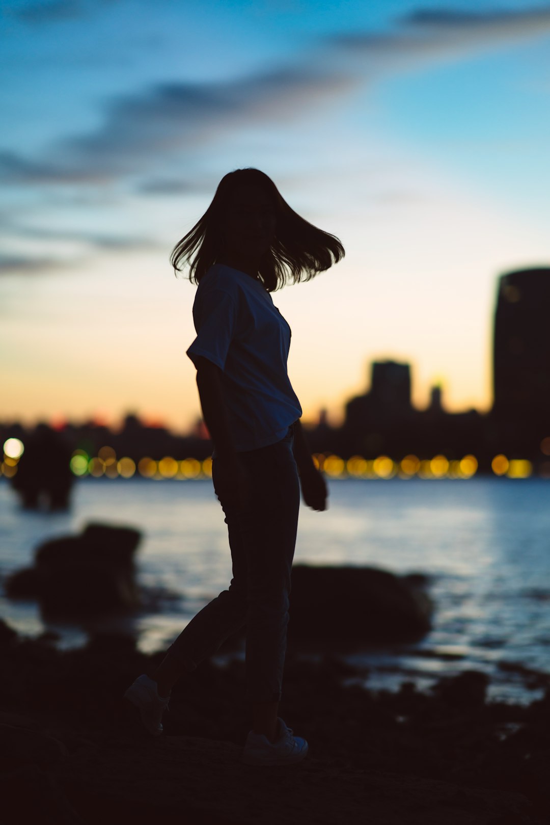 silhouette photography of woman standing near body of water