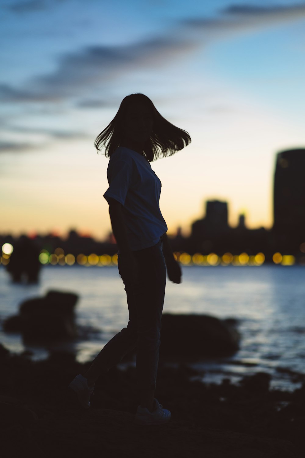 silhouette photography of woman standing near body of water