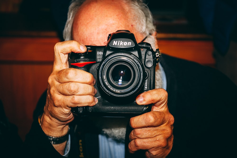 hombre sosteniendo una cámara Nikon negra